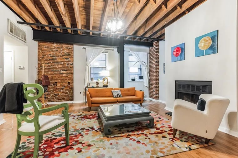 The living room of the Old City condo features exposed brick and beams.