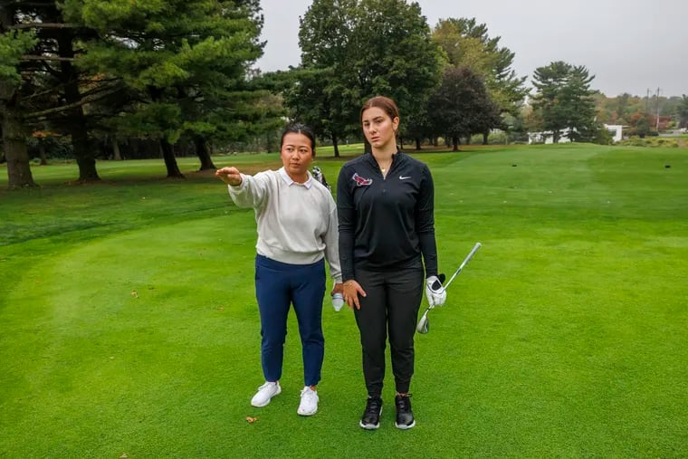 St. Joe's women's golf coach Theresa Luu looks over the green at first hole with freshman Ava Tornello at the Bala Golf Club.