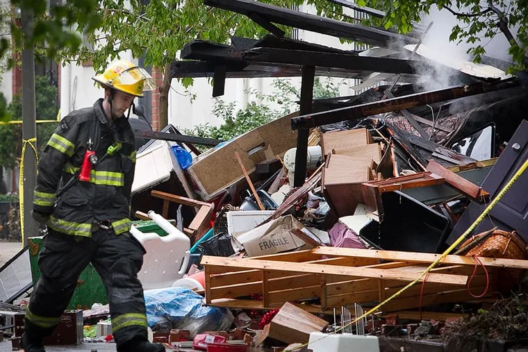 A firefighter walks past the wreckage of a home in the 2300 block of Naudain Street in Center City, destroyed in an explosion early Thursday morning.
