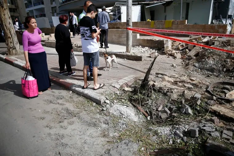 People stand near the damage inflicted by a rocket fired from Gaza after it hit in the southern Israeli port city of Ashdod, on Monday.