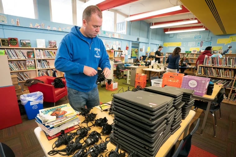 Mitchell Elementary School assistant principal Chris Kleinschmidt organizers power cords and laptops.