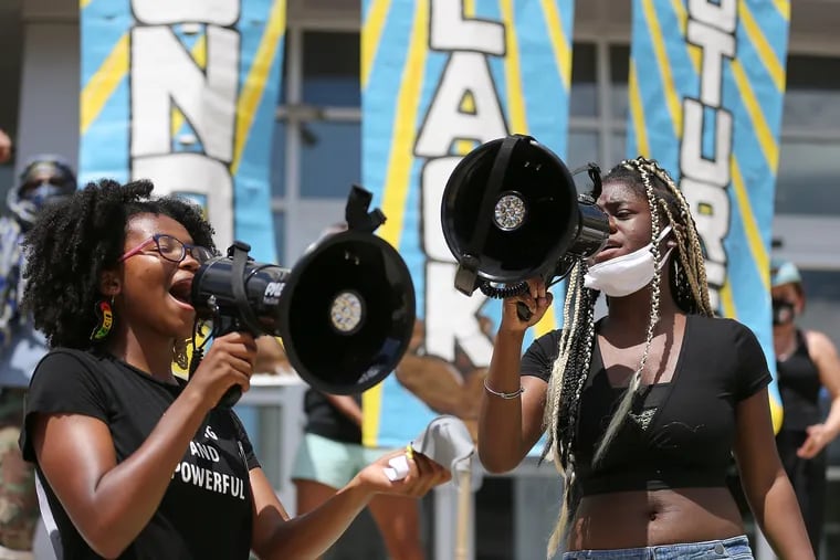 Rising seniors at Central High School Sheyla Street (left) and Samyah Smalley lead protesters in a song on Sunday.