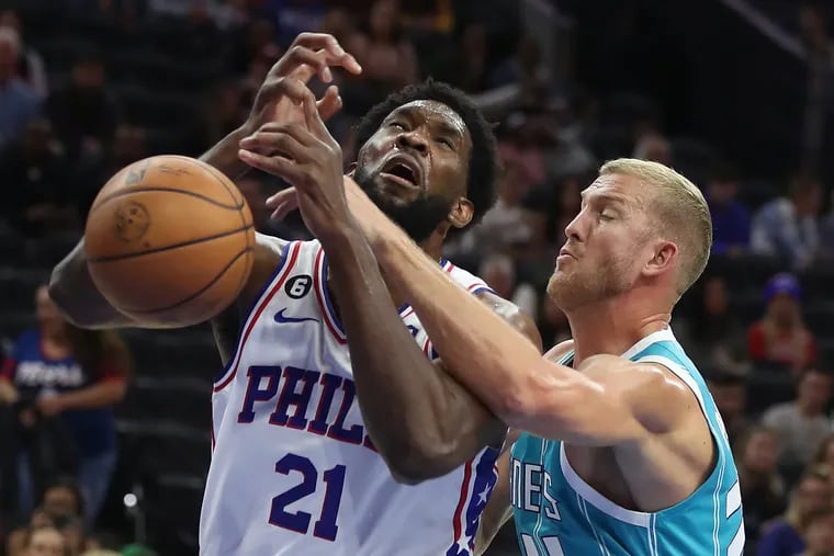 Joel Embiid, left, of the Sixers is fouled by Mason Plumlee of the Hornets during the first half of their preseason game at the Wells Fargo Center on Oct. 12, 2022.