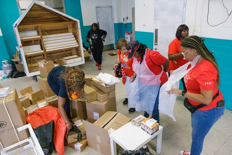 Divine Nine: Delta Sigma Theta Sorority members preparing to paint and place books on bookshelf (background) in the after school room at the Marian Anderson Recreation Center, S. 17th Street, Philadelphia, Wednesday, August 14, 2024. The sorority is at the recreation center as part of its Delta's Safe Haven Project. Members of the sorority painted computer and after school room, sorted books by African American authors as part of this service project.