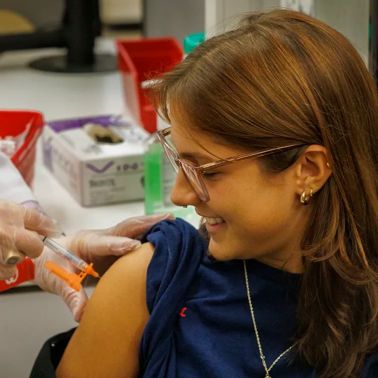 Alexandra Pompan, a customer service associate, gets vaccinated against COVID-19 by Dr. Philip Maceno, pharmacy manager at Walgreens, on Monday, October 23, 2023.