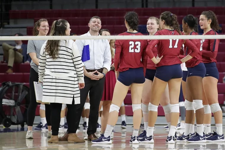 Penn volleyball head coach Iain Braddak (center) with his assistant coaches and some of his players during a match at the Palestra this season.