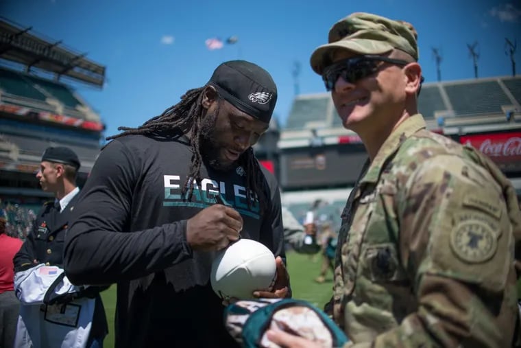 Eagles running back LeGarrette Blount signs a service member’s football during Sunday’s practice at Lincoln Financial Field.