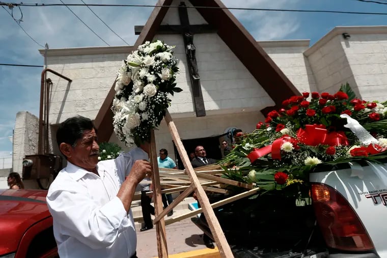 A man unloads funeral wreaths for a memorial service for Ivan Manzano, who was killed in the El Paso mass shooting, outside the Perches funeral home in Ciudad Juarez, Mexico, Friday, Aug. 9, 2019. Families of those killed when a gunman opened fire at an El Paso Walmart are gathering at funerals on each side of the U.S.-Mexico border to remember loved ones.