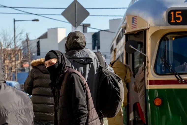 A transit customer wearing a mask to stay warm waits to board the trolley at the intersection of Girard Avenue and Front Street in Fishtown.
