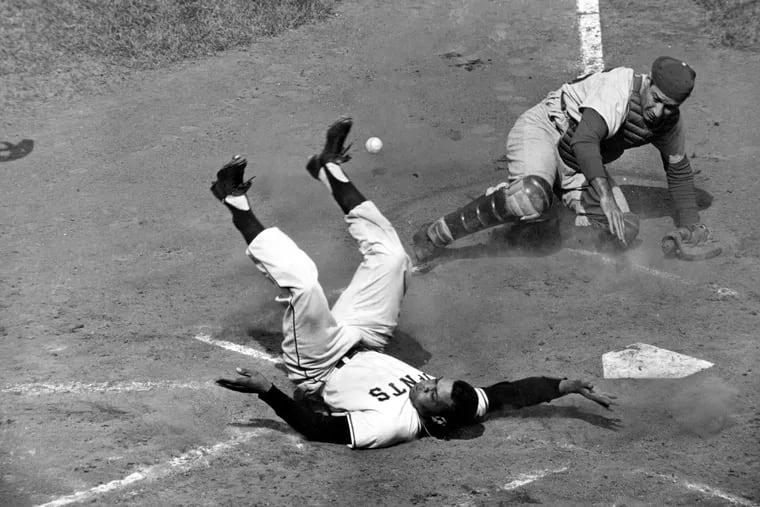 Willie Mays winds up on his back in a collision with Phillies catcher Joe Lonnett at home plate on an inside-the-park home run in 1957.