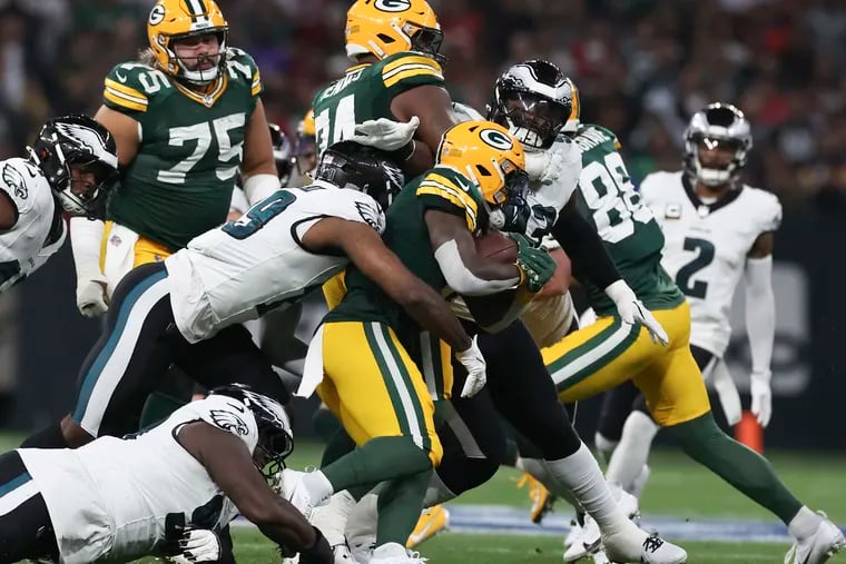 Eagles cornerback Darius Slay (right) looks on as linebacker Josh Sweat and defensive tackle Jordan Davis stop Green Bay Packers running back Josh Jacobs on Friday.