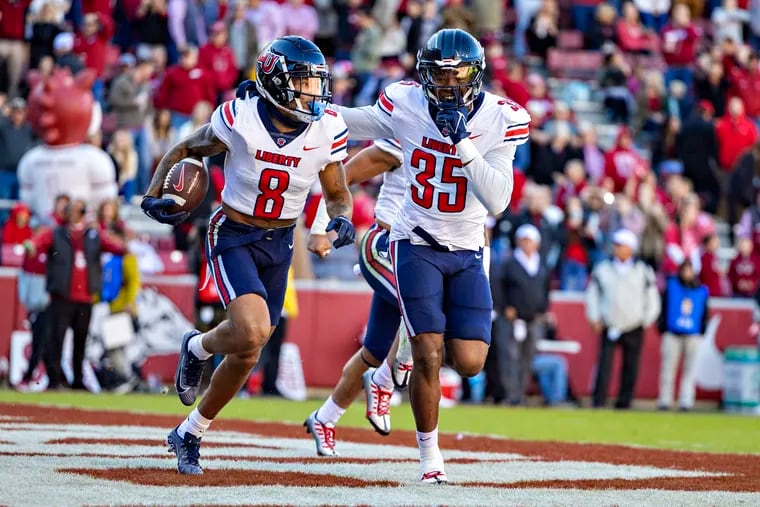 Liberty Flames teammates Daijahn Anthony (left) and Tyren Dupree (right) celebrate Anthony's end-zone interception during an upset victory at Arkansas in November. Liberty, which is 4-0 in bowl games, is an underdog against Toledo in Tuesday's Boca Raton Bowl. (Photo by Wesley Hitt/Getty Images)