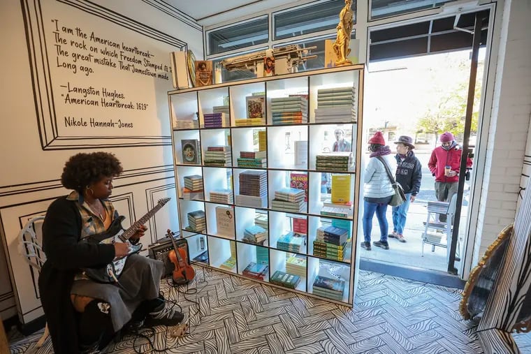 Faith the Violinist performs while customers browse through books on the sidewalk at Harriett’s Bookshop in Fishtown on Small Business Saturday.