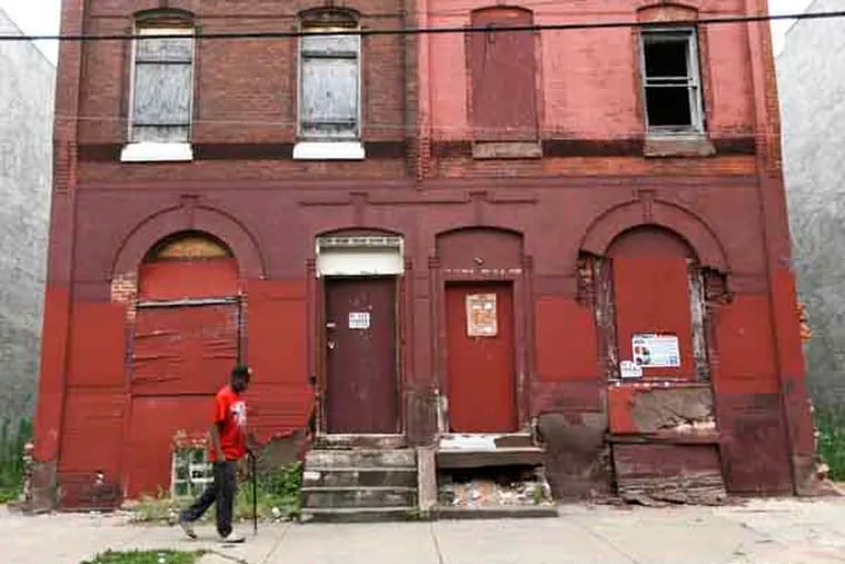 A man walks through a blighted neighborhood, Thursday, July 11, 2013, in Philadelphia. Mayor Michael Nutter announced Thursday an anti-poverty plan called "Shared Prosperity Philadelphia." (AP Photo/Matt Rourke)