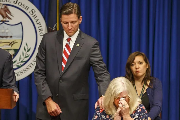 Daniel J. Dye, senior deputy attorney general, reaches over and comforts Judy Deavena, mother of Joey Behe, a victim of sexual abuse by a Catholic priest.
