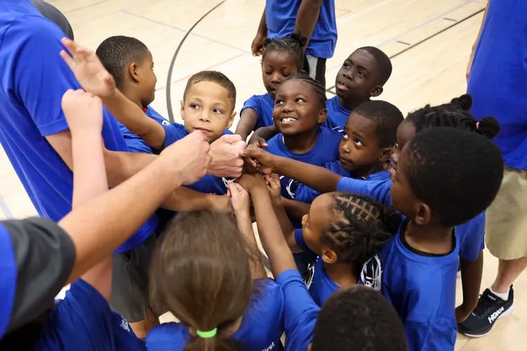 Kids gather in a huddle following a round of basketball drills during Healthy Hoops at the Columbia North YMCA in Philadelphia on Tuesday, July 23, 2024. Healthy Hoops combines a basketball camp with health education. This session of Healthy Hoops focused on asthma education.