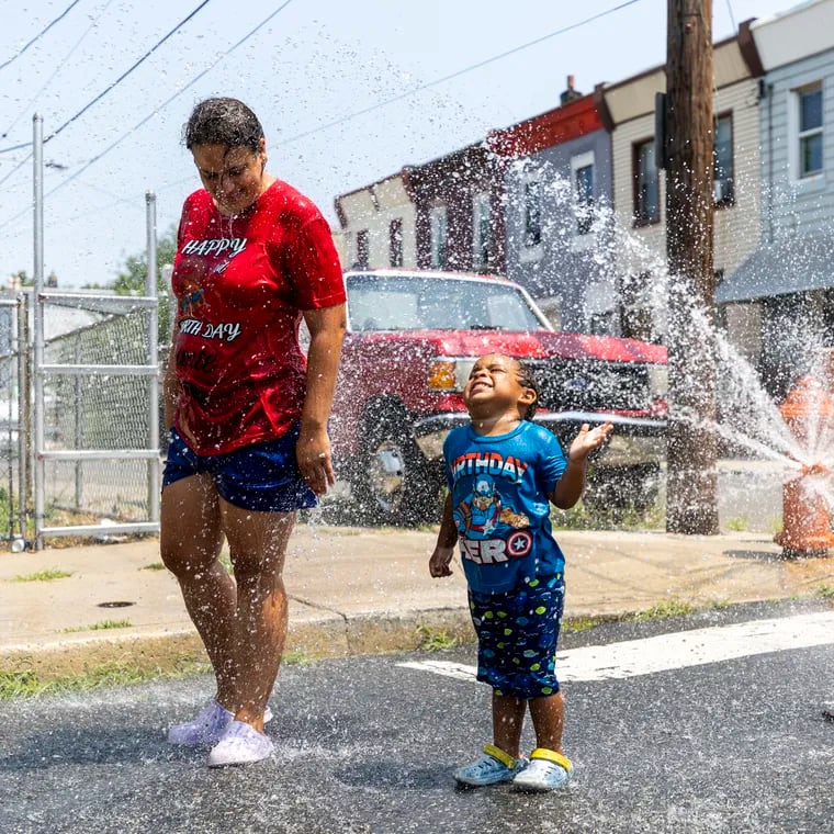 Alexandra Figueroa, 33, of Fairhill, cools off in the summer heat with her son Rubannyel Soto, 3, on Tuesday.