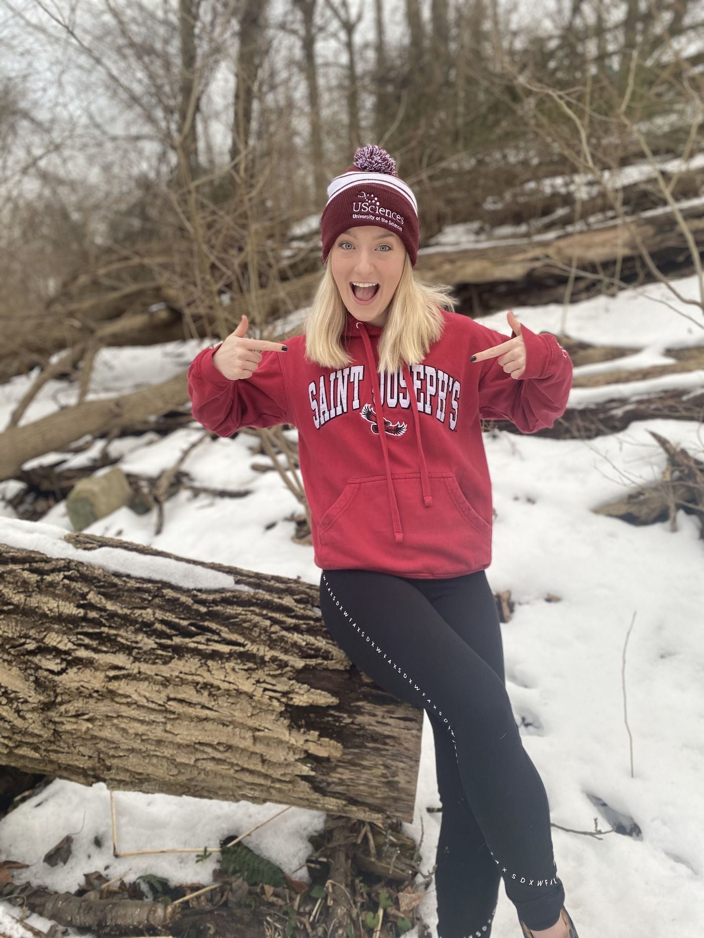 Jayna Suter, a senior at the University of the Sciences, wears a St. Joseph's University sweatshirt and USciences hat after learning about the proposed merger between the two universities.