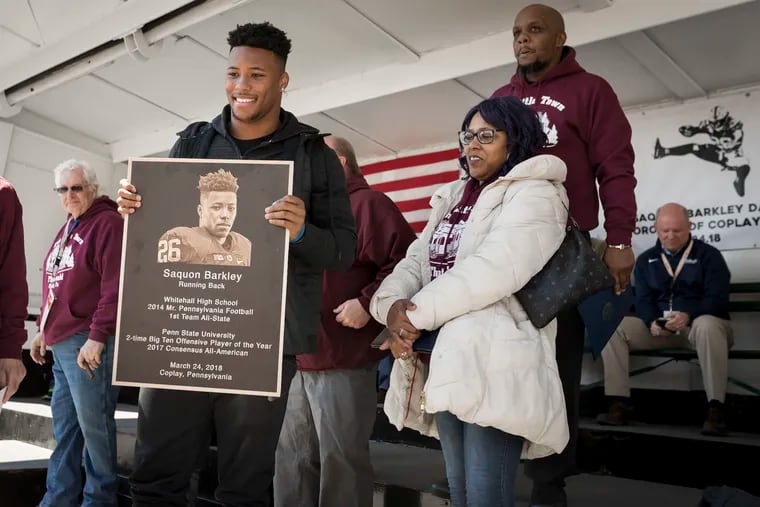 Former Penn State running back Saquon Barkley holds a plaque as he is honored by his hometown of Coplay, Pa., on Saquon Barkley Day, March 24, 2018. His parents, Tonya Johnson and Alibay Barkley, watch.