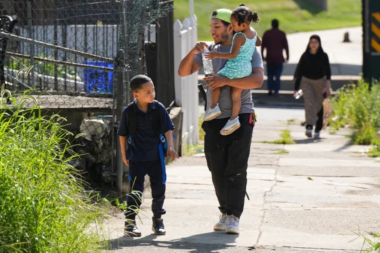 Wilson Caicedo walks his little sister Eva Baez, 2, and his little brother Tarek Baez, 5, home after picking Tarek up from Kindergarten, on a hot August day, in Philadelphia, August 27, 2024.