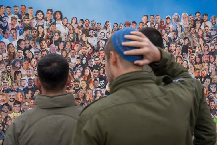 Israeli soldiers look at pictures of revelers killed on Oct. 7, 2023 at the Nova music festival by Hamas militants during a cross-border attack, as they visit the site in Re'im, southern Israel near the Gaza border, on Jan. 28, 2024.