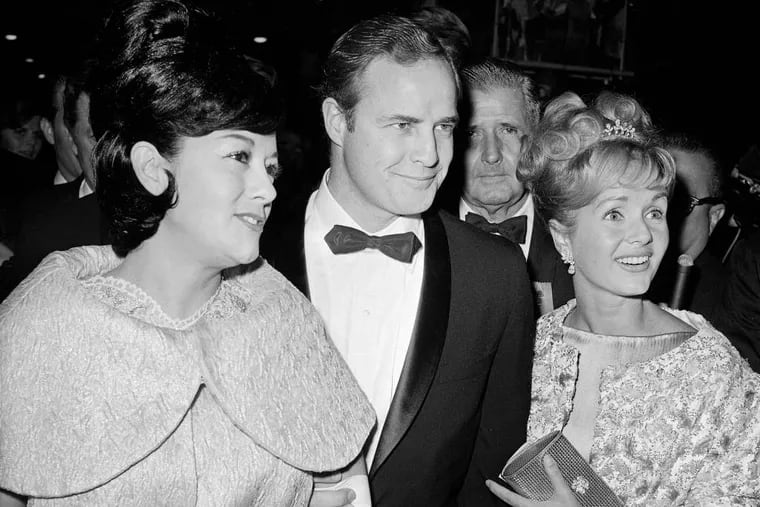 File: Marlon Brando, his wife, Mexican actress Movita Castaneda, left, and actress Debbie Reynolds, right, arriving for the West Coast premiere of "Mutiny on the Bounty" at the Hollywood Egyptian Theater in Los Angeles in November 1962. Castaneda, the dark-haired actress who met Brando on a movie set and later married him and had two of his children died Thursday, Feb. 12, 2015 at a Los Angeles rehabilitation center after being treated for a neck injury. The Los Angeles Times says Castaneda was believed to be 98. (AP Photo/David F. Smith,File)