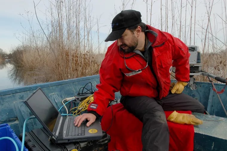 Professional explorer Vince Capone checks his laptop for readings as he guides a torpedo-shaped magnetometer attached to a boogie board through the Rancocas Creek in order to detect the submarine.