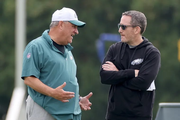 Eagles defensive coordinator Vic Fangio (left) and Eagles GM Howie Roseman talk at training camp on Sunday.