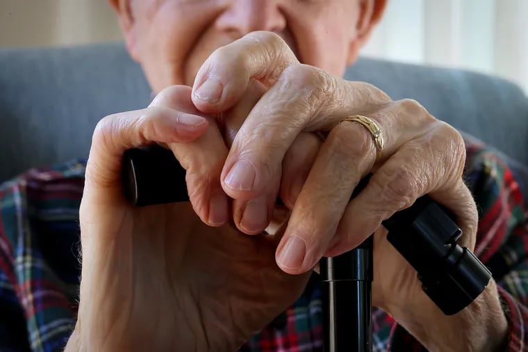 Charles Malloy, 99, rests his hands on his cane as he poses for a portrait at his home in West Chester on Wednesday, April 24, 2024.