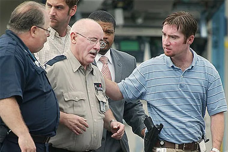 Joseph Walczak, center, is shown with a medic and Philadelphia police investigators soon after the armored car robbery in which two guards were killed. Walczak had been assigned to remain inside the armored car and received minor injuries. (Alejandro A. Alvarez / Staff Photographer)