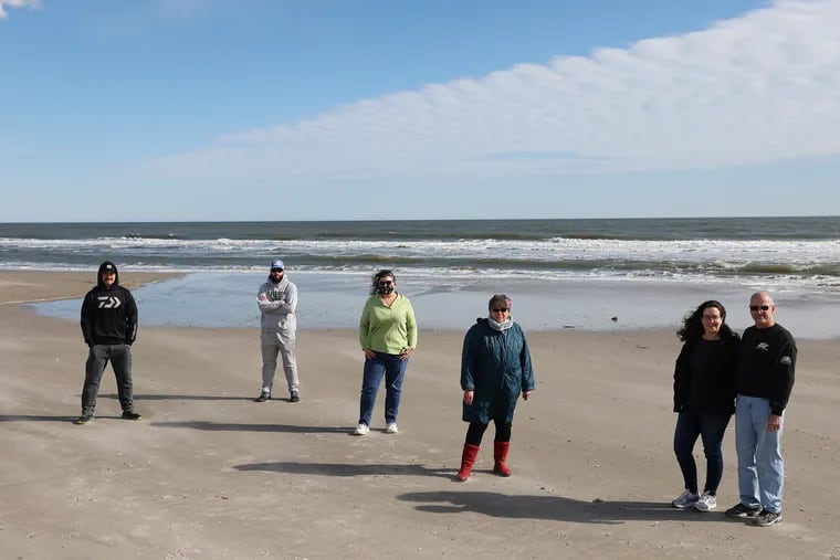 From left, Greg Cudnik, Tony Butch, Suzanne Hornick, Susan Cox, Tricia Conte, and Joe Conte stand on the beach in Ocean City, N.J., on Feb. 6. They are some of the Jersey Shore residents organizing against a planned offshore wind farm, saying it could negatively impact local infrastructure and fishing as well as spoil the view from the beach.