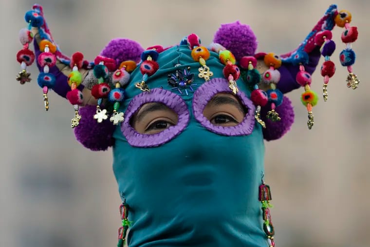 A costumed demonstrator joins in performing the feminist anthem, "A rapist in your path", during a demonstration against gender-based violence, one day ahead of International Women's Day in Santiago, Chile, Monday, March 7, 2022. The anthem has been adopted by activists across the world to denounce violence against women since first being performed in Chile during a wave of anti-government protests in 2019. (AP Photo/Esteban Felix)