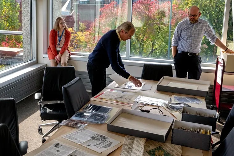 David K. O'Neil (center) looks through his personal archives now at the Kislak Center for Special Collections, Rare Books and Manuscripts at the University of Pennsylvania Libraries Monday, Oct. 14, 2024. O'Neil, a Penn alum and former manager of the Reading Terminal Market, has donated- and partially sold - his vast collection of business records, postcards, photographs, buttons, bags, and tens of thousands of photos related to public markets. Mitch Fraas, senior curator, Special Collections, is at right, with processing archivist Kristine McGee.