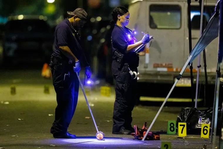 Philadelphia Crime Scene Unit officers and detectives investigate a multiple fatal shooting at North Alden Street above Girard Avenue  in West Philadelphia early Sunday morning.