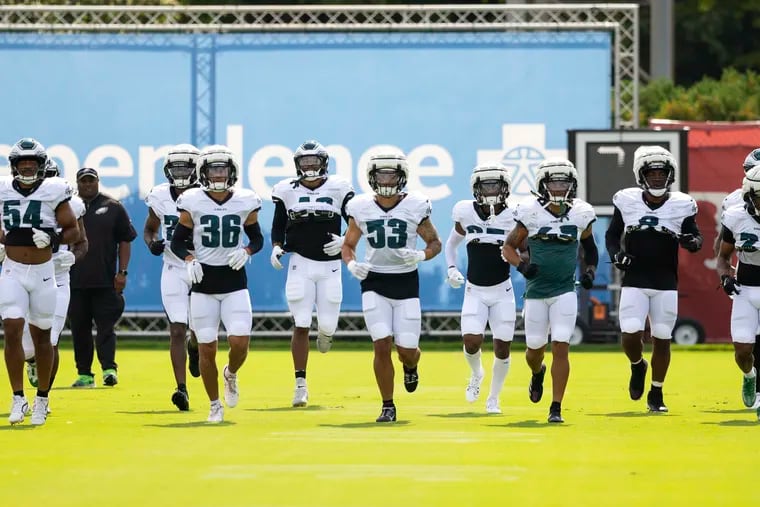 Linebacker Zack Baun (53) and the Eagles warm up Tuesday during their training camp workout, their first in full pads.