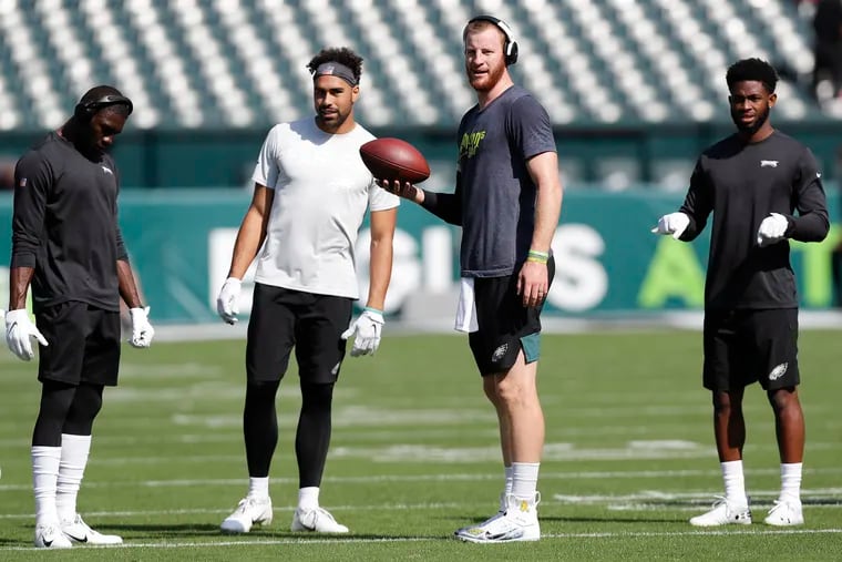 Eagles quarterback Carson Wentz holds the football with wide receivers (from left): Nelson Agholor, J.J. Arcega-Whiteside, and Greg Ward before the  Lions game.
