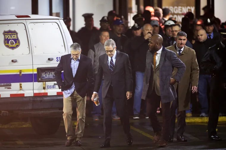 Philadelphia District Attorney Larry Krasner, center, and his Homicide Unit Chief Anthony Voci, left, walk away from the emergency room entrance at Temple University Hospital in North Philadelphia after SWAT Cpl. James O’Connor was fatally shot Friday, March 13, 2020. FOP members and police officers created a human barricade blocking Krasner from entering the hospital.