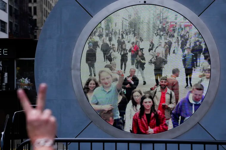 People in both New York and Dublin, Ireland, wave and signal at each other while looking at a livestream view of one another as part of an art installation on the street in New York in May.