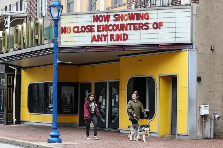 Sydney Kook walking "Hutch" and Niciole Troia walk under a sign of the times at The Colonial Theatre in Phoenixville.