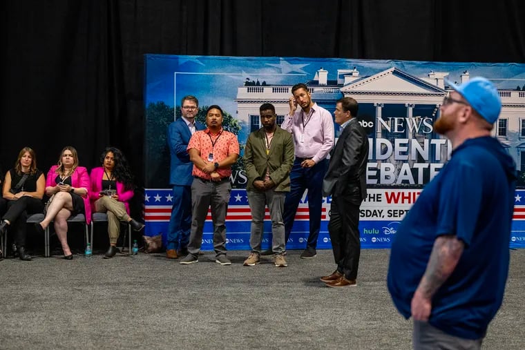 Staffers wait (and watch) for the end of Tuesday’s presidential debate, in the media center at the Convention Center. Afterward, they are the ones who hold up the signs with names of the candidates’ surrogates in the “spin room” while they are interviewed by reporters.