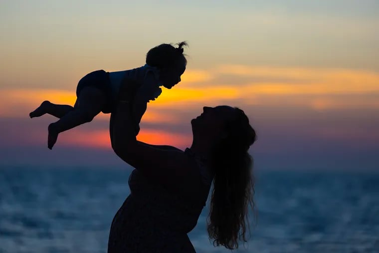 Brooke Johnson of North Jersey lifts up her daughter Elaina Dixon, 8 months old, at Sunset Beach in Cape May on Friday as they weather the first full day of summer.