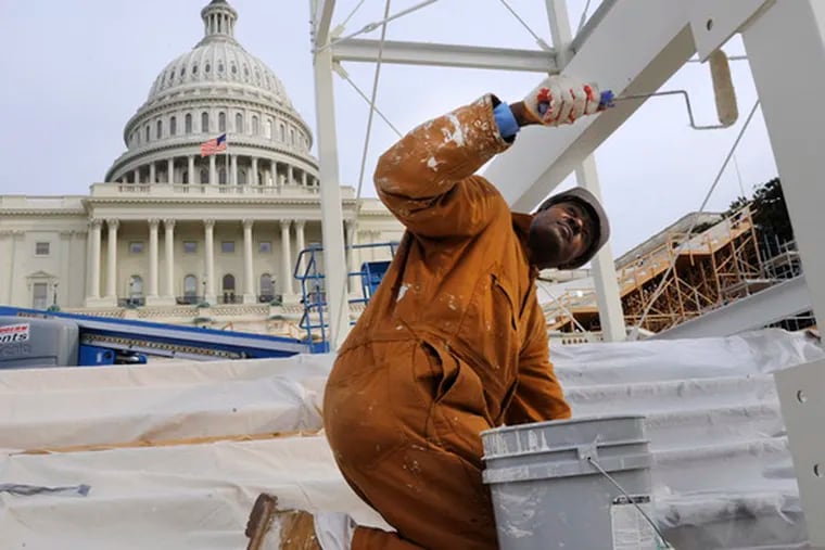 With the Capitol in the background, a worker paints the center stand of the inaugural platform. It should be dry by Jan. 20.