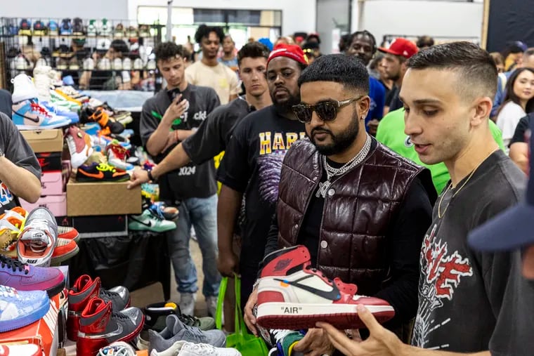 Canadian rapper NAV (center), is with Jonathan Dimodica, CEO of Got Sole, (right), as he visits a vendor to potentially buy some shoes at the sneaker convention on Saturday.