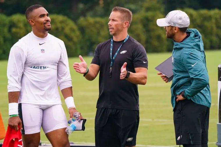 Eagles quarterback Jalen Hurts, left, talks with vice president of player performance Ted Rath, center, and offensive coordinator Shane Steichen, right, during practice at NFL football training camp, Thursday, July 29, 2021, in Philadelphia. (AP Photo/Chris Szagola)