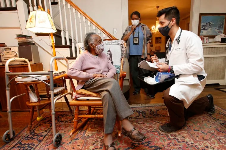 Nurse practitioner Tarik Khan talks to 101-year-old Jessie Birtha (left) with her 72-year-old daughter Becky Birtha listening before Khan administered leftover COVID-19 vaccine to the both of the women at their West Mount Airy home on Monday, March 8, 2021. Khan is from the Family Practice and Counseling Network.