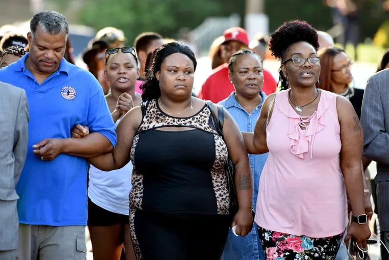 Nadia Syblis (center), the mother of homicide victim Sandrea Williams, takes part in a prayer walk on Thursday in West Philadelphia. At right is Williams’ aunt Yasheca Rhoden. At left is Ronald Ryan of Town Watch Integrated Services. Behind them are Williams’ aunt Naisha Rhoden (left) and grandmother Hyacinth Douglas (right).