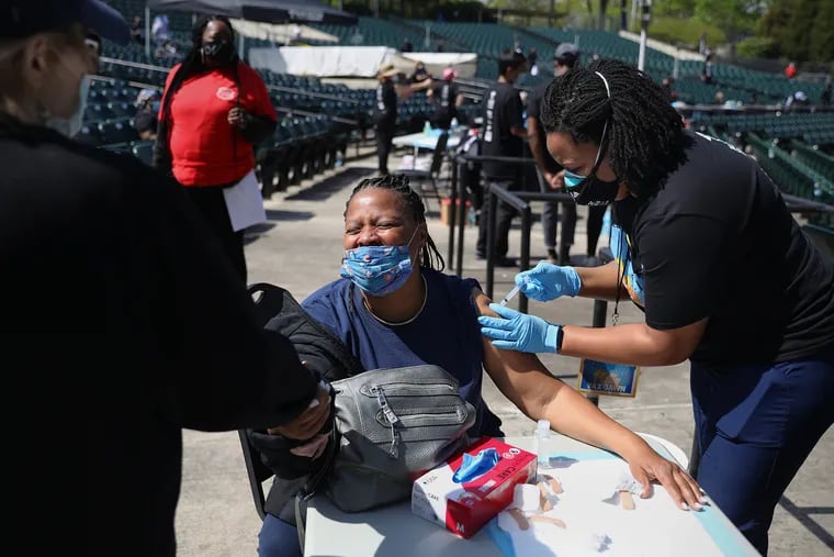 Carol Green (center) of Strawberry Mansion holds the hand of nurse Pat D'Antonio (left) as nurse Cydni Walker vaccinates her during the Philly Vax Jawn COVID-19 vaccine clinic at the Dell Music Center in Philadelphia's East Fairmount Park on Saturday. Green said she was afraid of needles but afterward said the shot went smoothly.