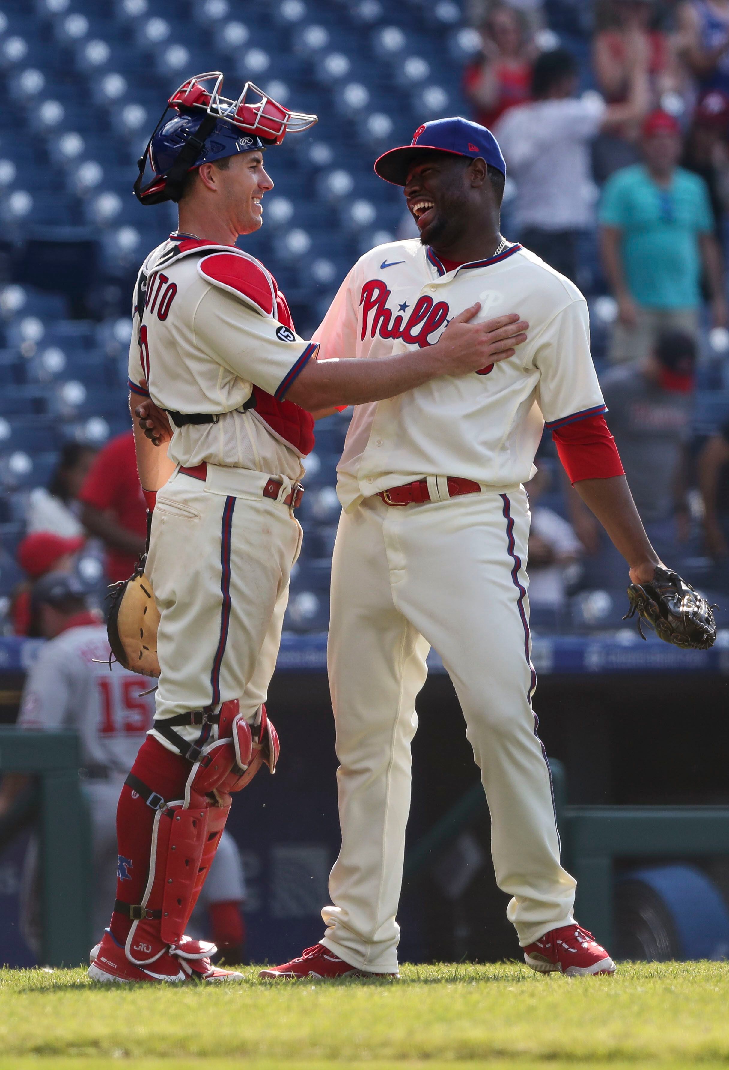 Philadelphia Phillies - Rhys Hoskins, wearing the cream Phillies uniform,  celebrating with the dugout after scoring a run.