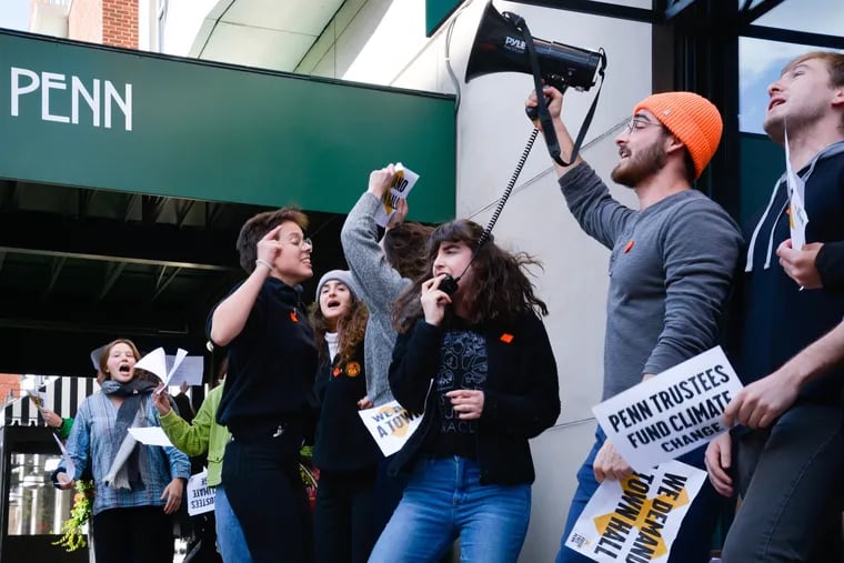 Sophomore Emma Glasser (center with megaphone mic) leads the protest on fossil fuels outside the building where Penn's board of trustees were meeting.