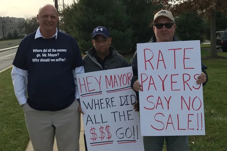 Joe Stafford of Upper Chichester (left), Bill Barber of Chester (center), and Ron Navin Upper Chichester protest outside Merenda Hall at Neumann College before a meeting of the Chester Water Authority board, which is split among members from Chester City, Delaware County, and Chester County on Nov. 21.
